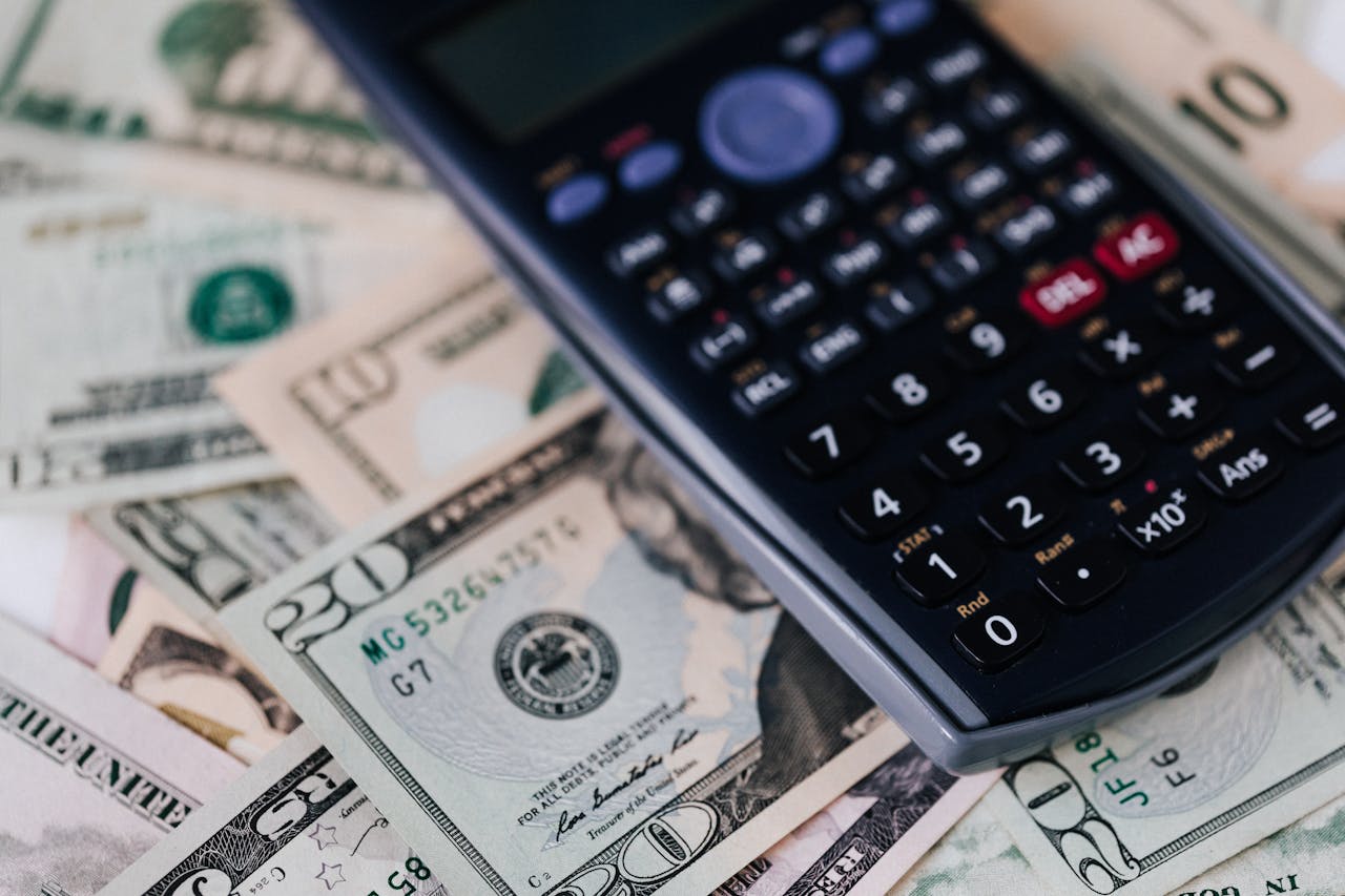 From above of electronic calculator placed over American cash paper money for budget planning and income and expenses calculation